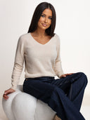 Jasnobeżowy sweter OH HONEY PURE ze 100% wełny merino na siedzącej modelce – dekolt w serek i prążkowane mankiety.