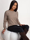 Sweter OH HONEY DELICATE ze 100% kaszmiru w kolorze taupe na siedzącej modelce – okrągły dekolt i prążkowane mankiety.
