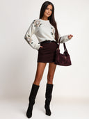 Sweter w kwiaty OH HONEY WINTER ROSE w kolorze ecru — cała sylwetka z przodu w stylizacji z burgundowymi spódniczko-spodenkami.