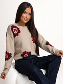 OH HONEY WINTER ROSE — beżowy sweter z wełną merino i kaszmirem na siedzącej modelce, zbliżenie na burgundowe kwiaty.